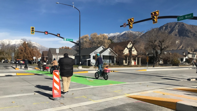 Tráfico en intersección con carril bici verde,ciclistas,semaforo,señales de tráfico, montañas nevadas al fondo.Movilidad urbana en Durango.