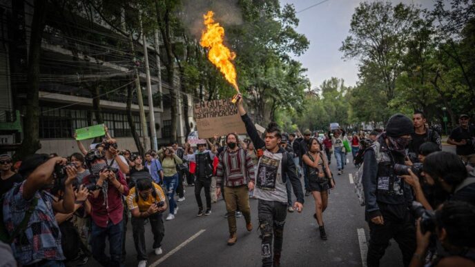 Manifestantes en CDMX protestan contra el aumento de rentas y la gentrificación, uno alza una bengala. Medida busca beneficios para inquilinos.