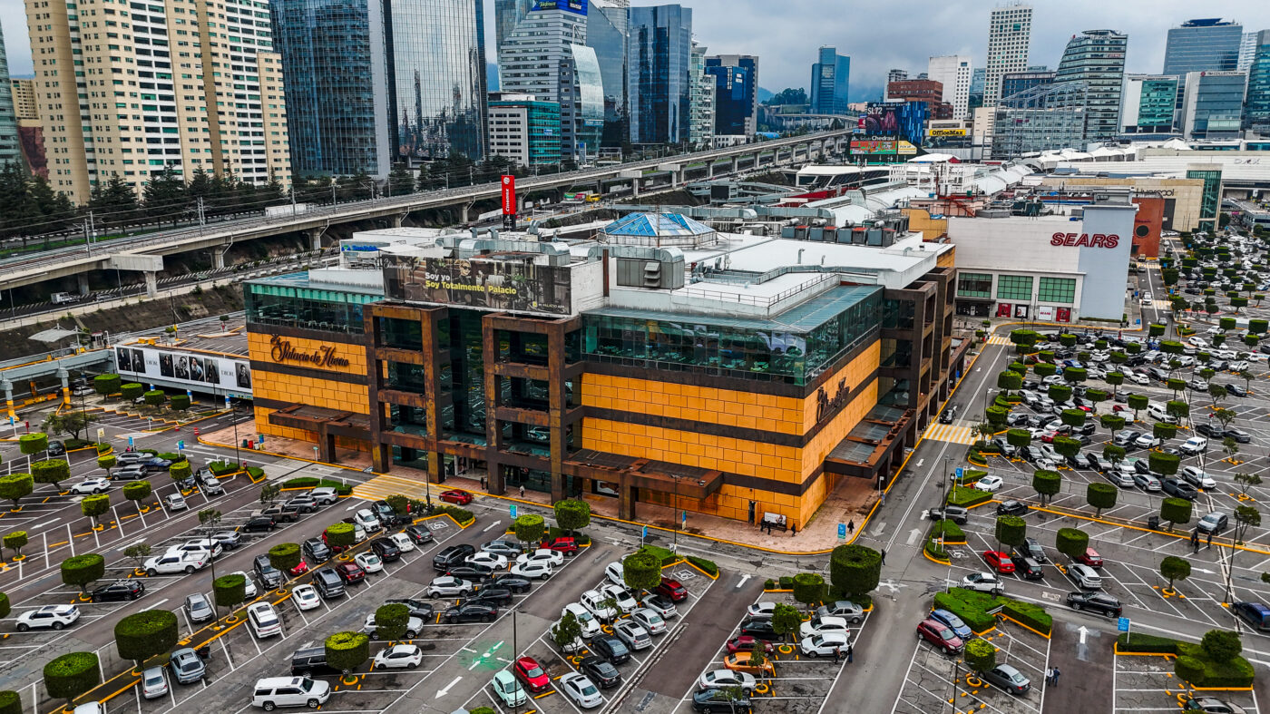 Vista aérea de Antara Fashion Hall, uno de los centros comerciales líderes en CDMX, con tiendas departamentales y estacionamiento lleno. Arquitectura moderna.