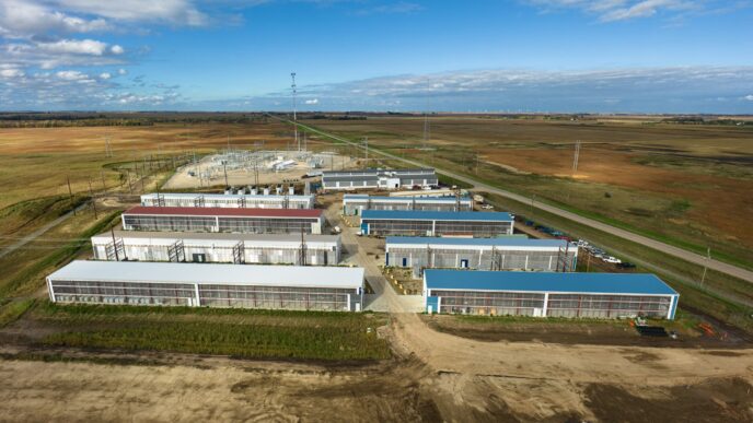 venue/architecture
Vista aérea de un complejo industrial con edificios largos y bajos, rodeado de campos. Infraestructura de energía visible.