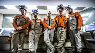 Cinco trabajadores de aceros largos sostenibles con cascos y ropa de trabajo, inspeccionando la producción. Certificación FDES para Aceros Largos.