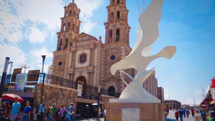 Arquitectura en Chihuahua, México, con escultura moderna y catedral histórica. Destino clave para Inmobiliare Summits LATAM.