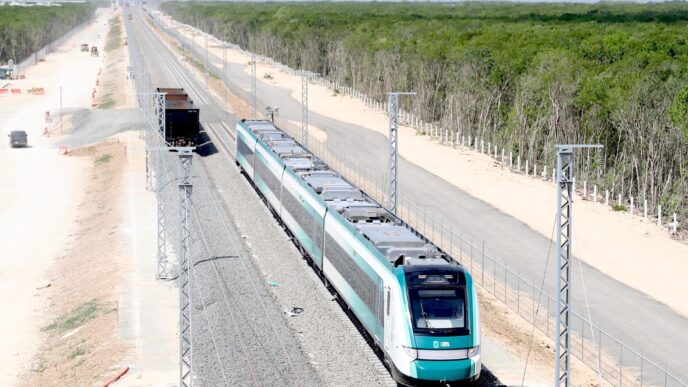 Trenes de pasajeros en vías férreas, presentados por Claudia Sheinbaum. Moderno transporte y selva de fondo. Imagen de la nueva línea ferroviaria.