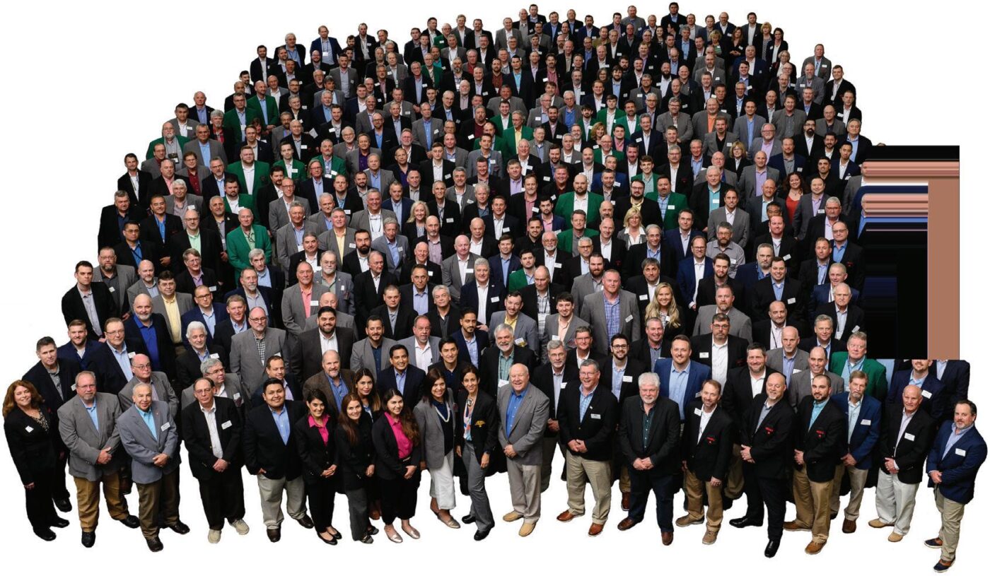 Gran grupo de personas vestidas formalmente, posiblemente asociadas con Clio Asset Management y Builders FirstSource, reunidas para una foto grupal.