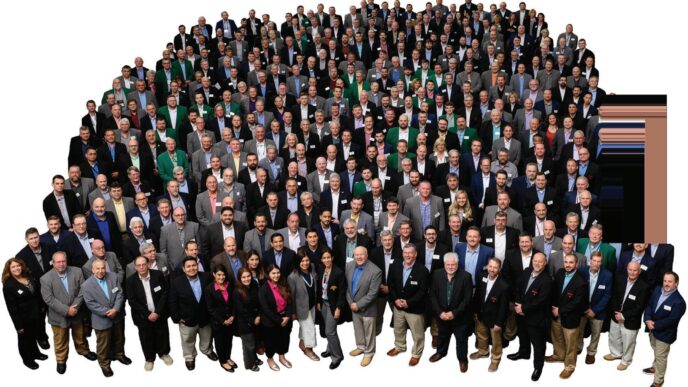 Gran grupo de personas vestidas formalmente, posiblemente asociadas con Clio Asset Management y Builders FirstSource, reunidas para una foto grupal.