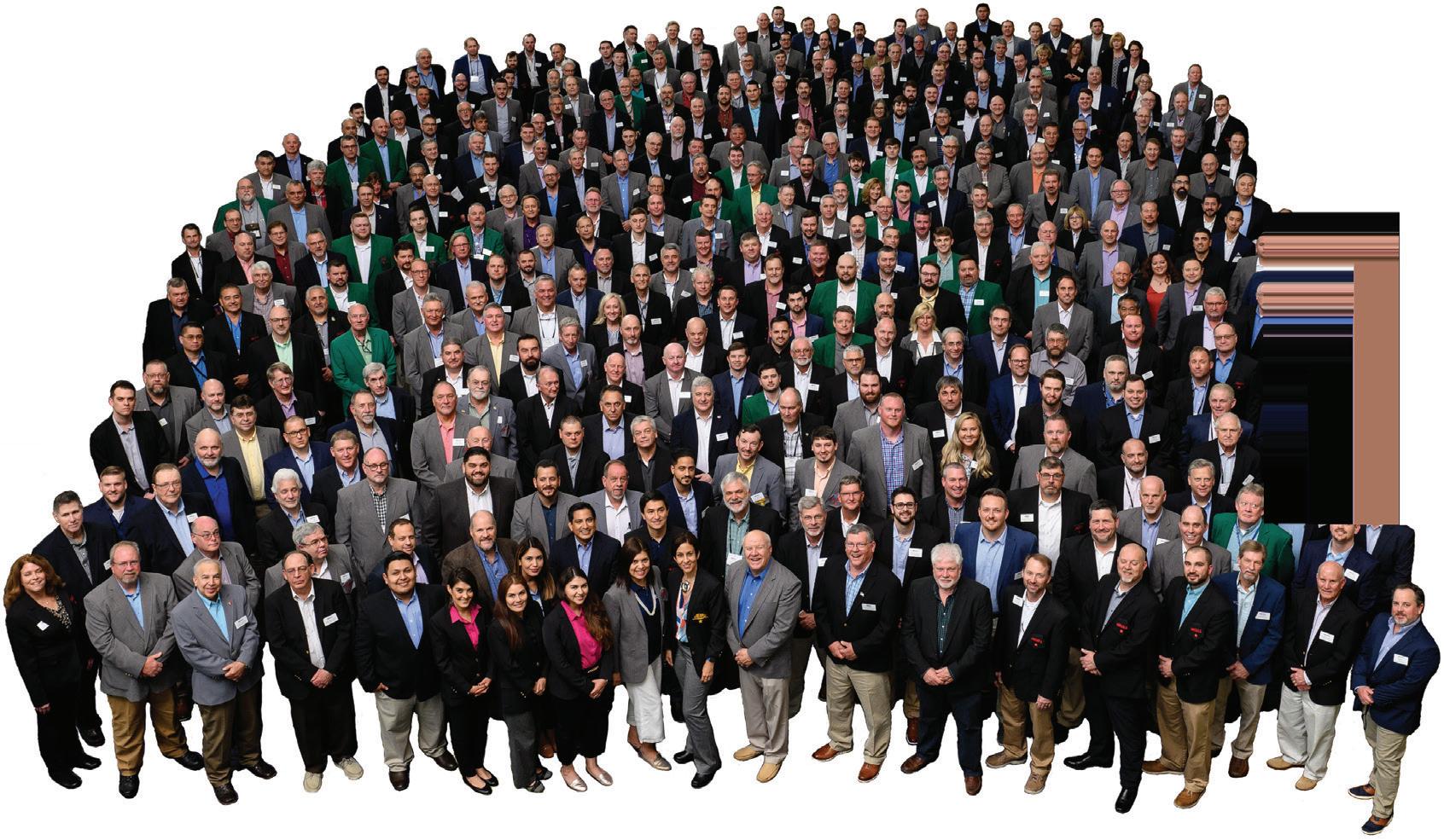 Gran grupo de personas vestidas formalmente, posiblemente asociadas con Clio Asset Management y Builders FirstSource, reunidas para una foto grupal.