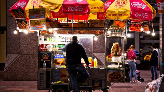 Carreta de comida en México, con sombrillas de Coca-Cola y Nikas, ofreciendo hot dogs, pretzels y knishes. Propuestas para mejorar carretas visibles.