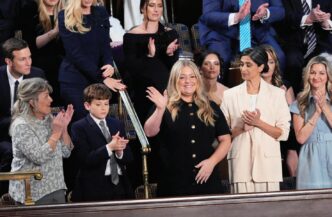 Attendees at an event, some clapping, one waving, in a formal setting. Government priorities, CMIC obras, Claudia Sheinbaum's administration.