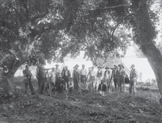 Category: venue/architecture
Grupo de hombres con equipos de topografía al aire libre, posiblemente en México. Arquitectura histórica en blanco y negro.