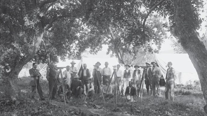 Category: venue/architecture
Grupo de hombres con equipos de topografía al aire libre, posiblemente en México. Arquitectura histórica en blanco y negro.
