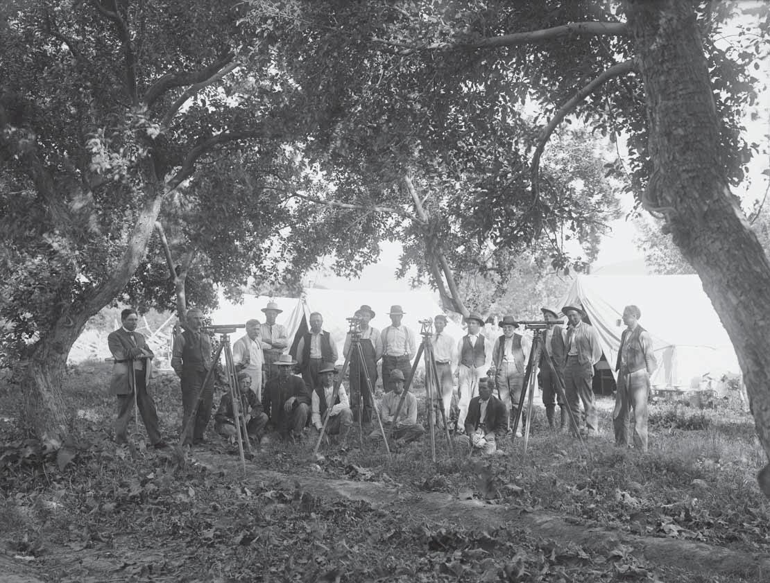 Category: venue/architecture
Grupo de hombres con equipos de topografía al aire libre, posiblemente en México. Arquitectura histórica en blanco y negro.