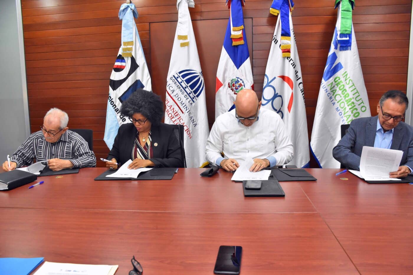 Sponsors/branding.

Firmando acuerdo en evento Inmobiliare Summits. Representantes de real estate en mesa con banderas de República Dominicana. Conferencia LATAM.