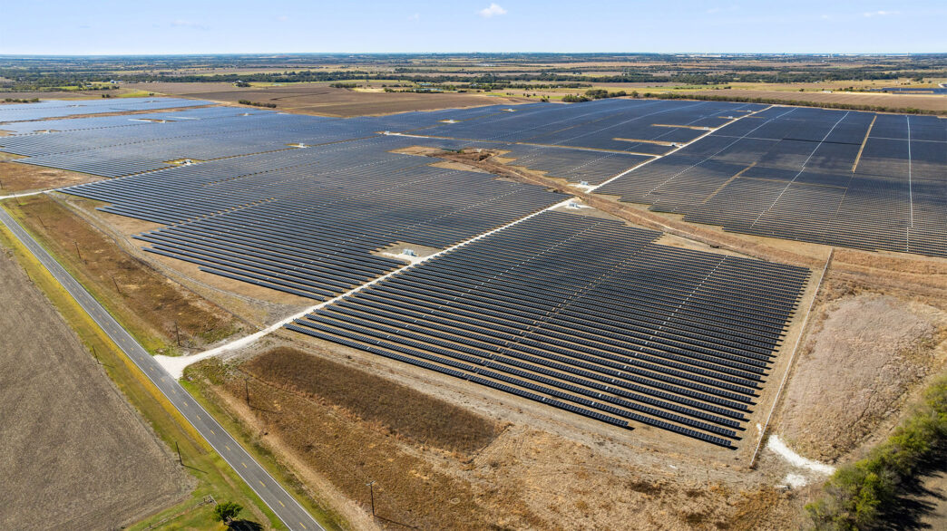 Vista aérea extensa de paneles solares, reflejando la colaboración hacia un futuro energético sustentable en campus, enfocada en energía limpia.