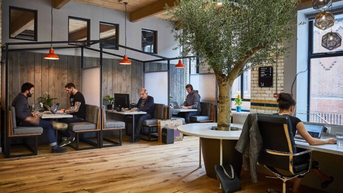 Venue/architecture.

Espacio de coworking moderno con personas trabajando en sus computadoras portátiles. Diseño biofílico con árbol interior. Oficina, trabajo, diseño.