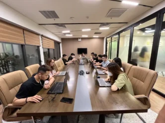 Reunión sobre nearshoring en vivienda: equipo trabajando en laptops en sala de conferencias. Estrategias para aprovechar el nearshoring en vivienda.