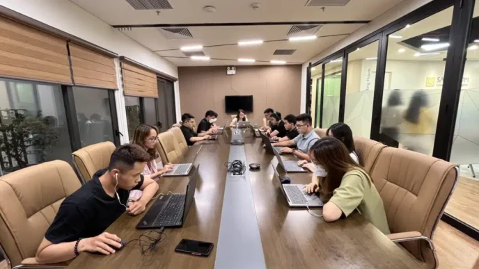 Reunión sobre nearshoring en vivienda: equipo trabajando en laptops en sala de conferencias. Estrategias para aprovechar el nearshoring en vivienda.