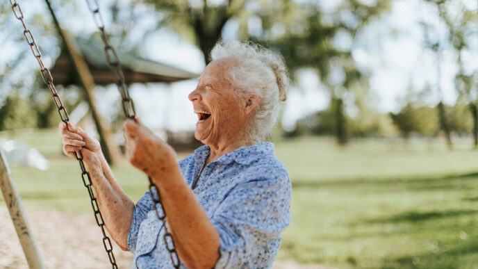 Una mujer mayor ríe mientras se balancea en un columpio. El real estate ofrece espacios para todas las edades. Inmobiliare Summits.