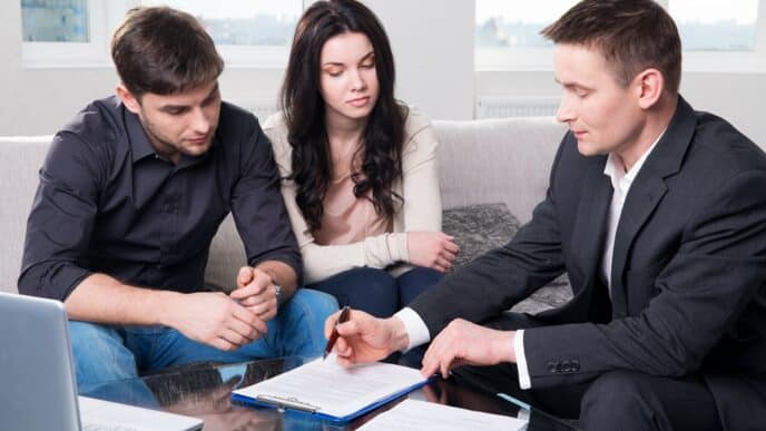 Here's the alt text for the image:

Asesor de bienes raíces explica contrato a pareja. Inversión en real estate en México y LATAM.