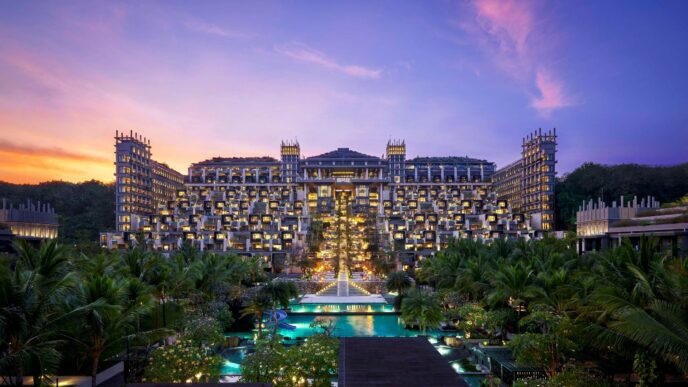 Vista de hotel en Bali al atardecer. Arquitectura moderna, piscinas iluminadas. Compromiso industria hotelera Bali con sostenibilidad.