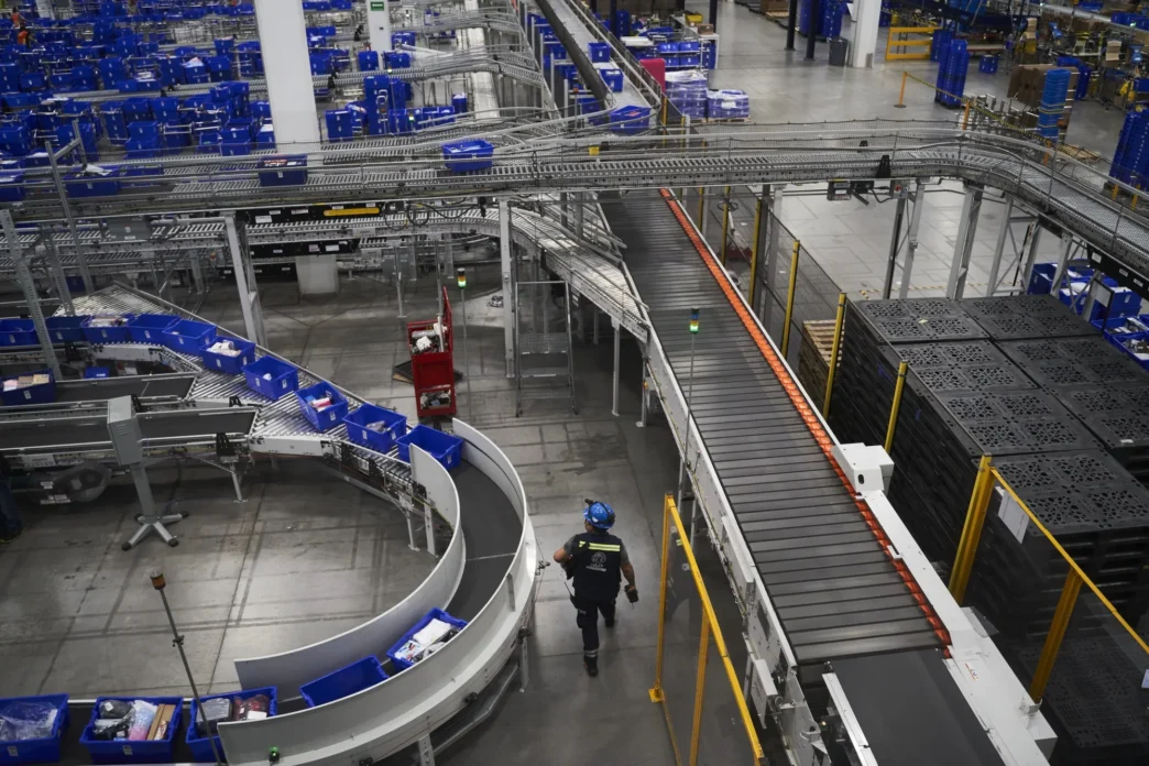 venue/architecture
Vista aérea de la logística moderna en México, un tema clave en Inmobiliare Summits. Bandas transportadoras y operario reflejan la eficiencia del real estate industrial.