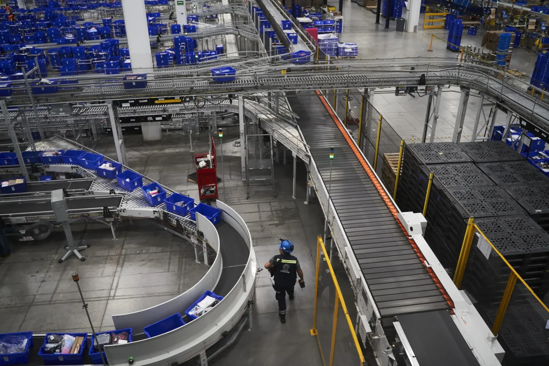 venue/architecture
Vista aérea de la logística moderna en México, un tema clave en Inmobiliare Summits. Bandas transportadoras y operario reflejan la eficiencia del real estate industrial.