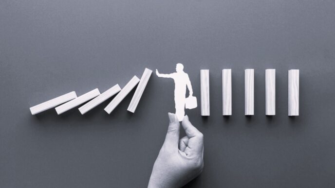 Conceptual: Deteniendo el efecto dominó. Mano sosteniendo figura de persona que impide la caída de bloques. Implicaciones en real estate, México.