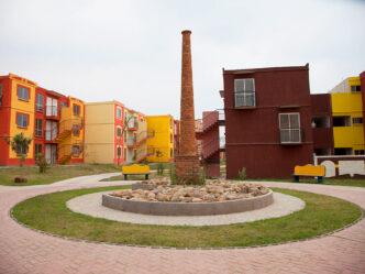 Conjunto habitacional colorido en México, con casas de Infonavit y una chimenea central. Interés en comprar casa propia en aumento.