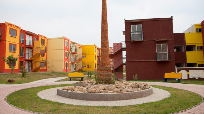 Conjunto habitacional colorido en México, con casas de Infonavit y una chimenea central. Interés en comprar casa propia en aumento.