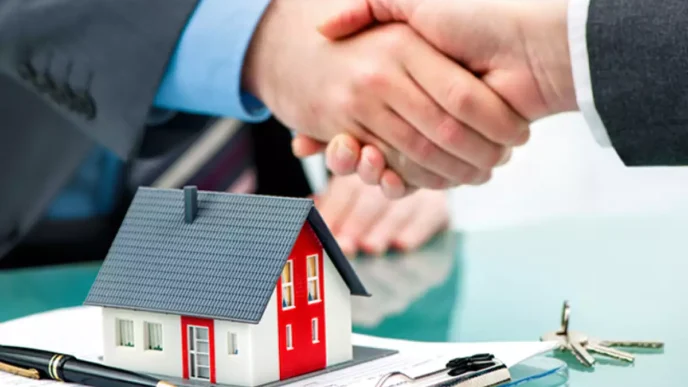 Concepto de inversión en bienes raíces: apretón de manos sellando un acuerdo. Casa modelo, pluma y llaves. Crédito Casa, financiamiento.