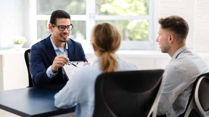 Reunión sobre crédito hipotecario: Agente explica el trámite a una pareja. Personas clave en el proceso de obtener un crédito hipotecario