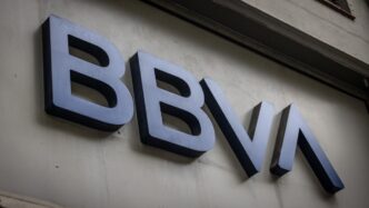 Logotipo de BBVA en pared, asociado a créditos hipotecarios. Instituciones públicas lideran el mercado según BBVA. Imagen informativa y corporativa.