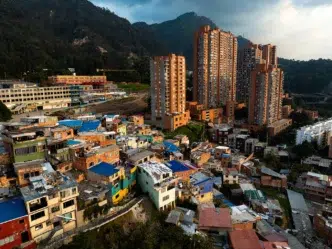Contraste en Colombia: Viviendas humildes en primer plano y edificios altos al fondo, reflejando la situación de la vivienda en 2024 en Colombia.