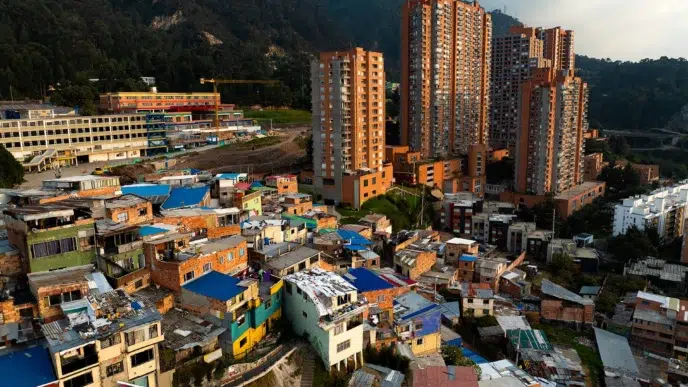 Contraste en Colombia: Viviendas humildes en primer plano y edificios altos al fondo, reflejando la situación de la vivienda en 2024 en Colombia.
