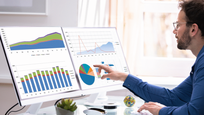 Análisis de datos. Hombre revisando gráficas en dos pantallas. Estrategia de inversión en bienes raíces.