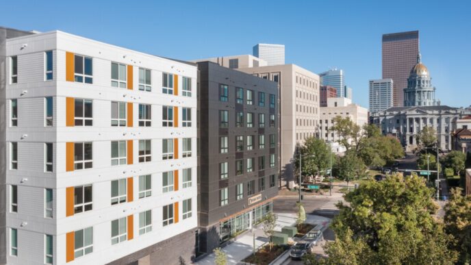 Edificio moderno en Denver, diseño de vivienda asequible con toques naranjas y vistas al capitolio. Arquitectura sostenible e innovadora en primer plano.