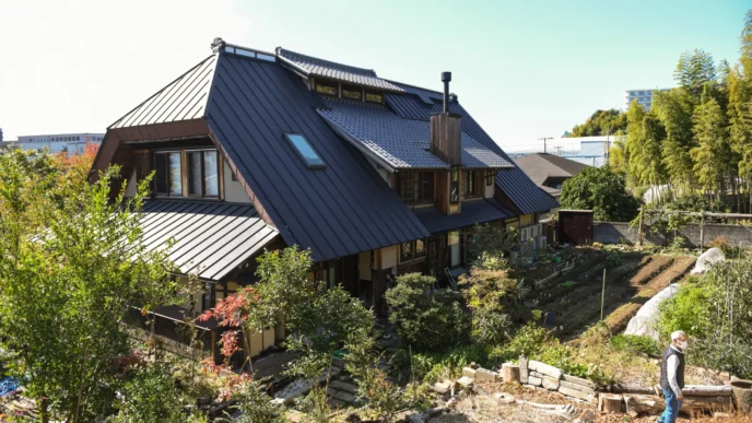 Vista de una casa sostenible con tejado a dos aguas en South East, rodeada de vegetación y un huerto. Un nuevo horizonte para la arquitectura ecológica.