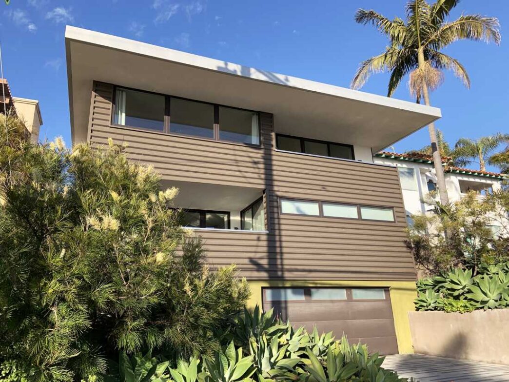 Fachada moderna de casa con eficiencia energética y diseño innovador. Real estate transformado con arquitectura sostenible y palmera imponente.