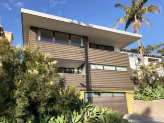 Fachada moderna de casa con eficiencia energética y diseño innovador. Real estate transformado con arquitectura sostenible y palmera imponente.