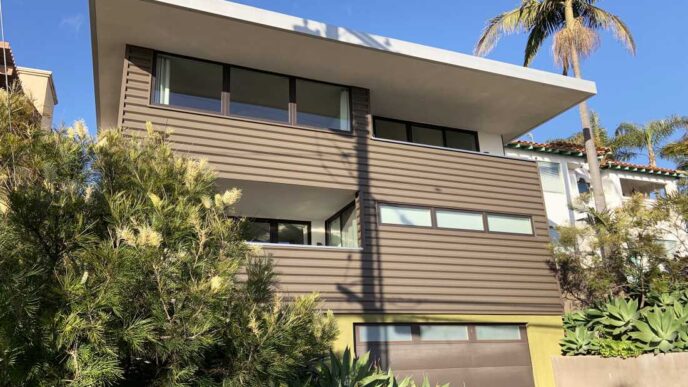 Fachada moderna de casa con eficiencia energética y diseño innovador. Real estate transformado con arquitectura sostenible y palmera imponente.