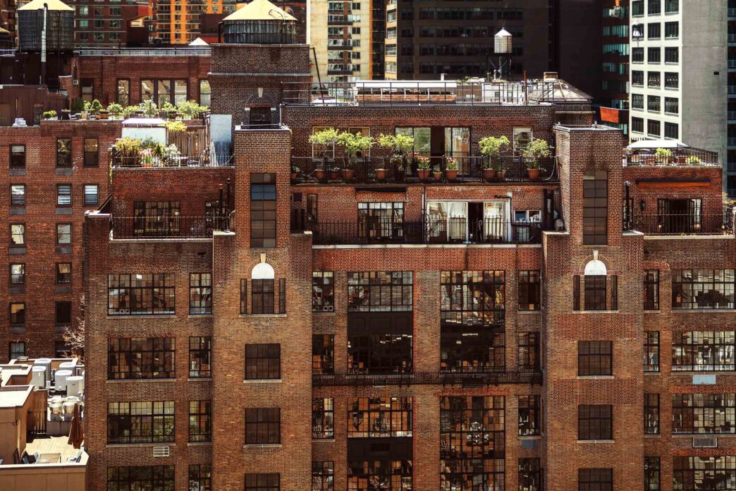 Edificio de ladrillo en NYC con plantas en la azotea, reflejando el impacto de la Ley Local 97 en el real estate. Arquitectura y sostenibilidad urbana.