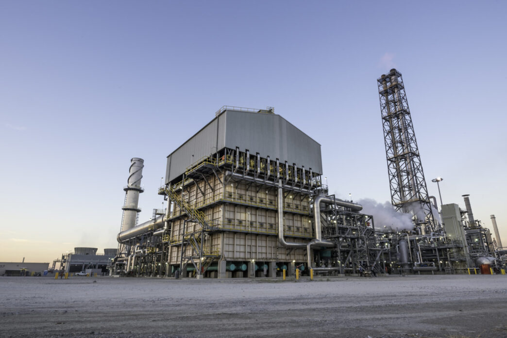 Vista de la planta de amoníaco Blue Point, con tecnología verde. Estructuras industriales, tuberías y chimeneas bajo un cielo despejado. Impacto tecnológico.