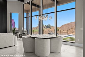 Interior de lujo con mesa redonda y vistas panorámicas a paisajes desérticos. Inversión en real estate de alto standing y diseño moderno.