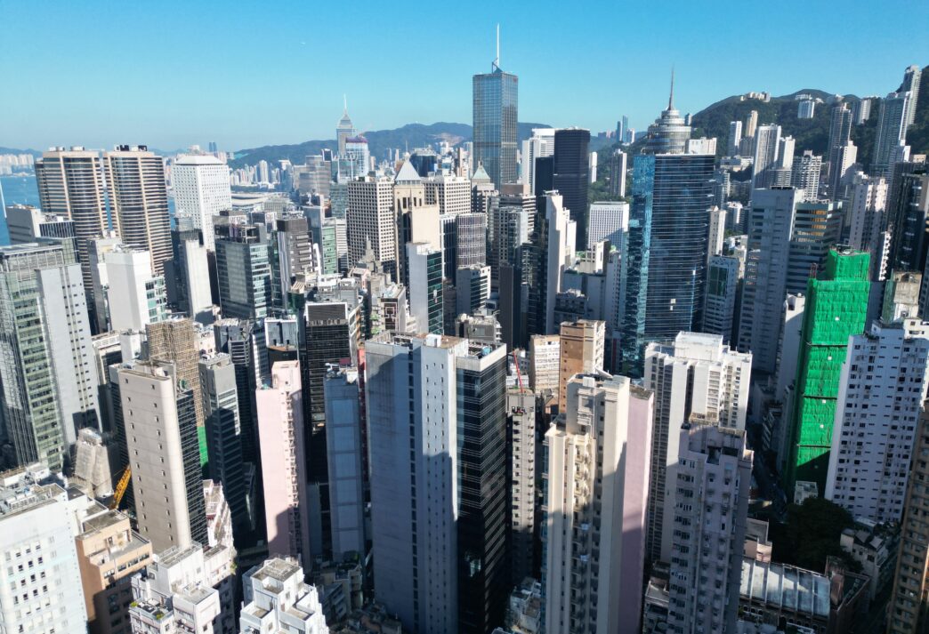Vista aérea de Hong Kong mostrando el auge del mercado inmobiliario de lujo con rascacielos y edificios modernos bajo un cielo despejado.