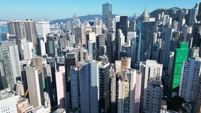 Vista aérea de Hong Kong mostrando el auge del mercado inmobiliario de lujo con rascacielos y edificios modernos bajo un cielo despejado.