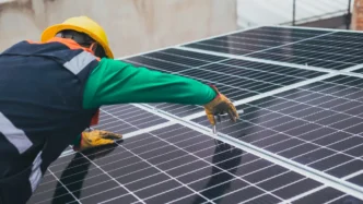 Instalación de paneles solares fotovoltaicos en Chedraui por Energía Real. Técnico con casco amarillo ajustando paneles. Energía renovable en tiendas.