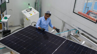 Trabajadora inspecciona paneles solares en fábrica de India. Energía solar impulsa el sector inmobiliario con sostenibilidad y tecnología avanzada.