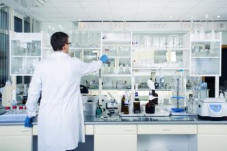 Investigador en laboratorio farmacéutico, parte de la infraestructura de energía verde, manipulando equipo. Acuerdo innovador para sostenibilidad.