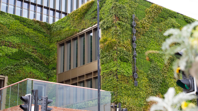 Fachada verde del edificio Foundation en Manchester, ejemplo de espacios sostenibles y Real Estate verde que redefine la arquitectura urbana con vegetación.