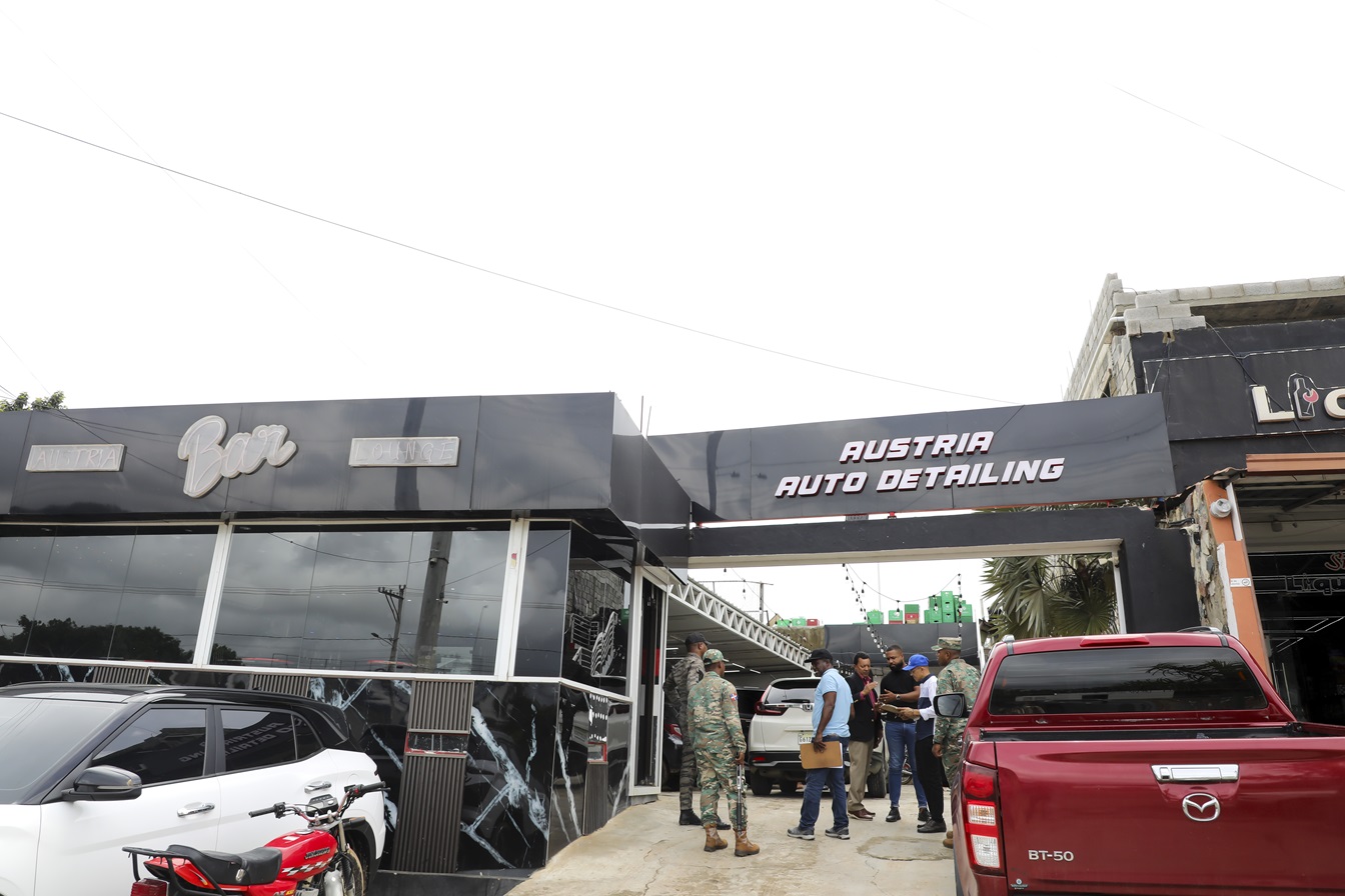 The image doesn't seem to be related to the keywords provided. I will provide an alt text based on the image content.

Exterior de Austria Auto Detailing y Bar, con personas y vehículos. Fachada moderna en blanco y negro.