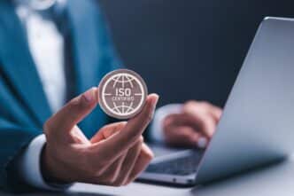 Sponsors/branding.

Mano sostiene insignia ISO Certified frente a laptop. Home Depot Chihuahua Norte, certificación LEED impulsa sostenibilidad en bienes raíces México.